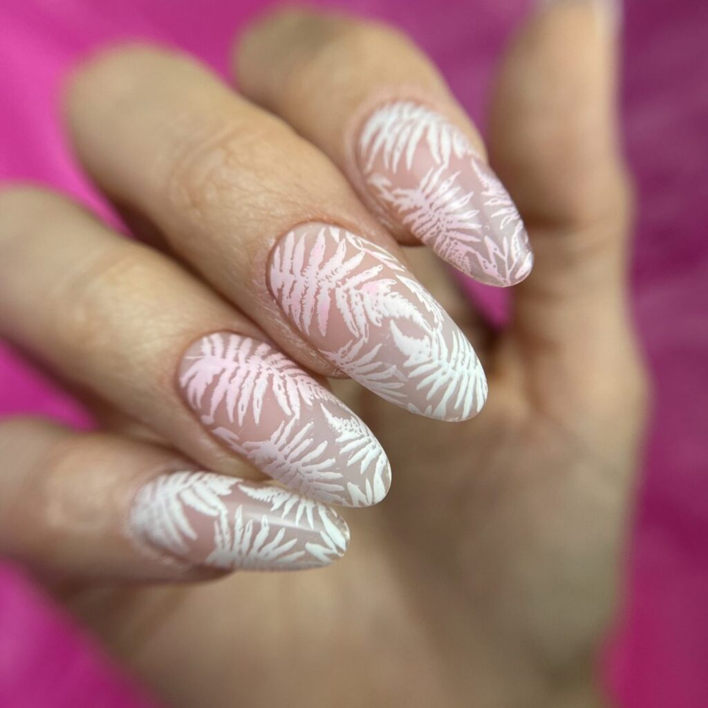 Uñas almendradas rosas con hojas estampadas en blanco