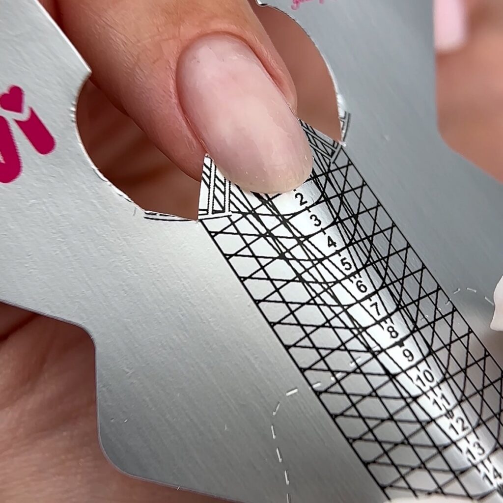 Molde de papel colocado bajo el borde de una uña para alargarla