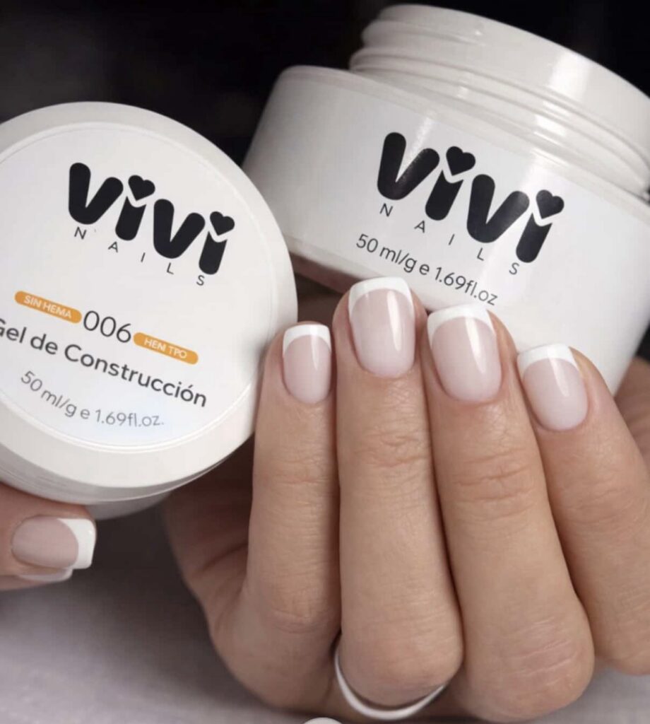 Manicura francesa en uña corta junto a dos tarros de gel de construcción Vivi Nails