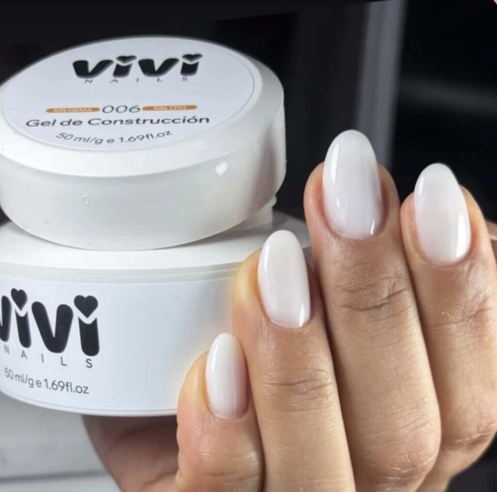 Mano con uñas blancas lechosas sujetando un tarro de gel de construcción Vivi Nails