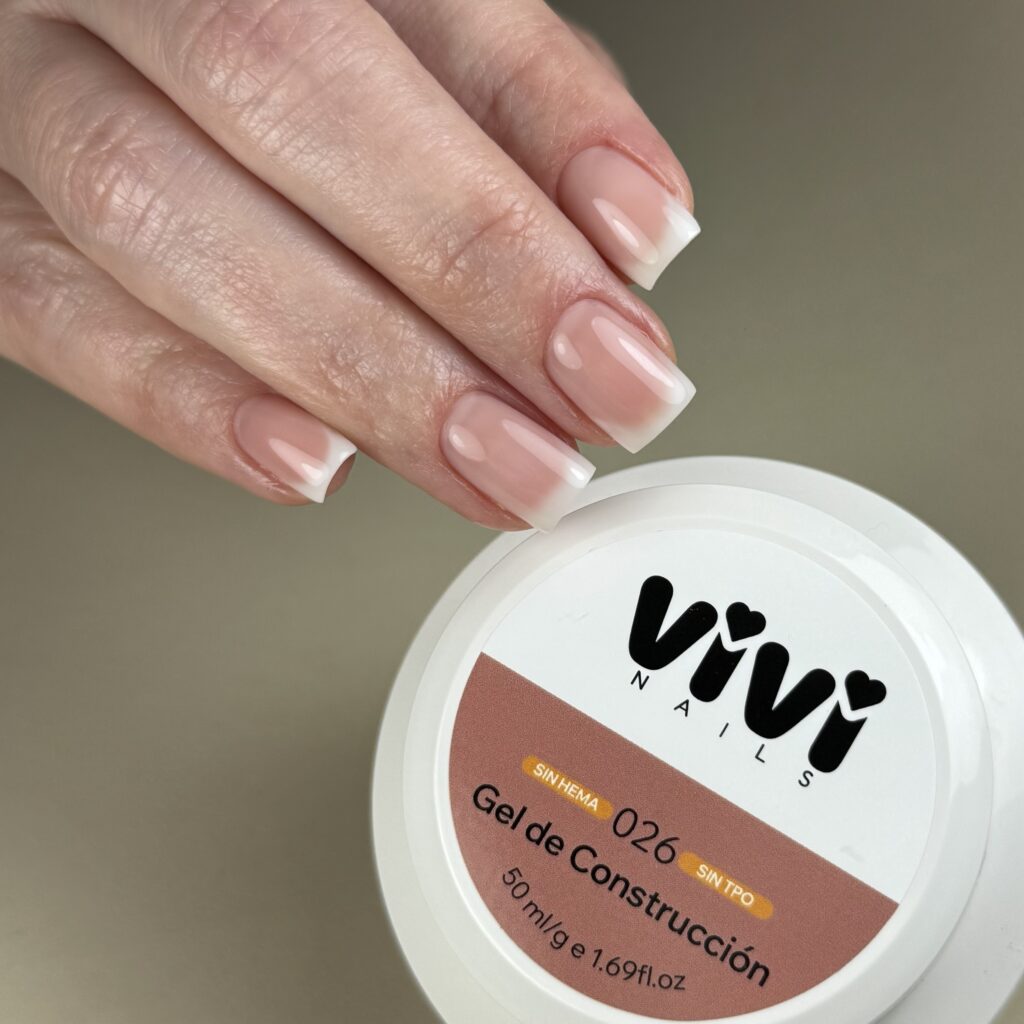 Manicura francesa sobre base rosada junto a un tarro de gel de construcción Vivi Nails